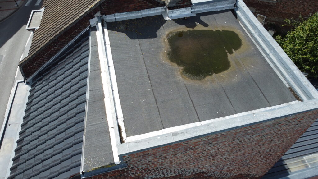 Toit plat avec eau stagnante, inspection par drone pour détection de fuites et d'endommagements.